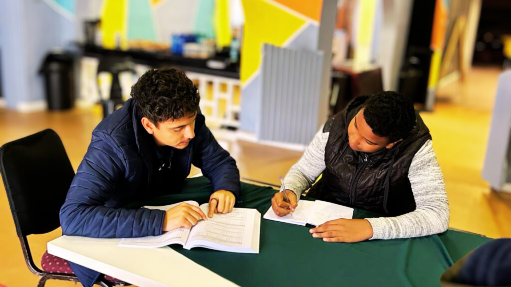 Upside volunteer busy with tutoring a Grade 8 learner